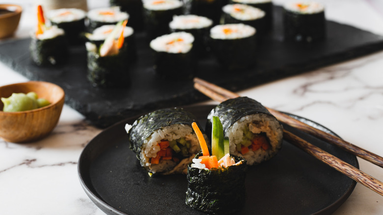 three sushi pieces on a plate with chopsticks