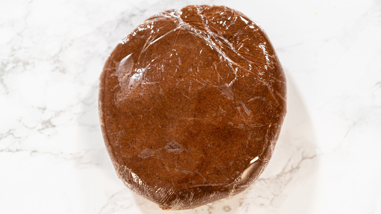 Chilling gingerbread cookie dough in plastic wrap before baking