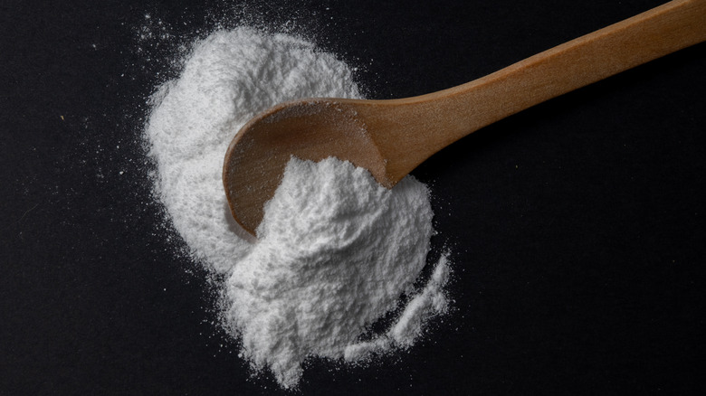 Baking soda on wooden spoon and black background