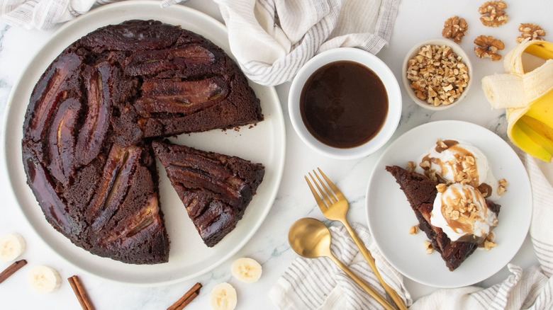 Bananas Foster brownie with slices removed next to bowl of sauce and serving on plate with ice cream