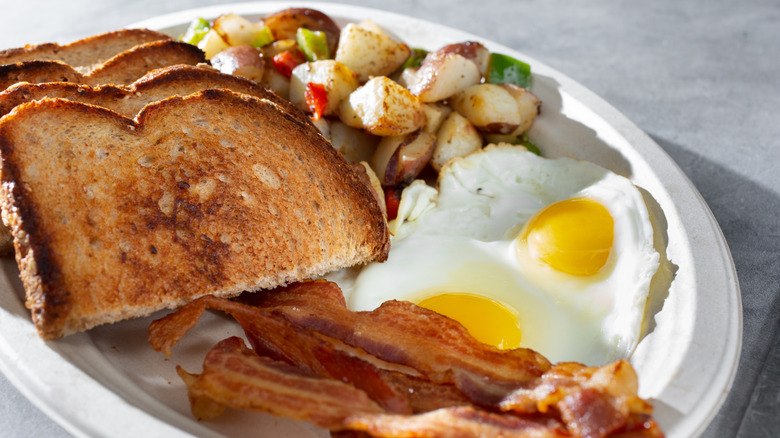 Dish of eggs, toast, bacon, and potatoes