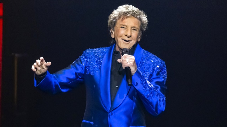 Barry Manilow sings onstage dressed in a bedazzled blue jacket.