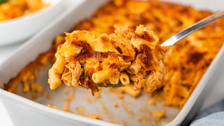 Spooning BBQ chicken mac & cheese out of baking dish