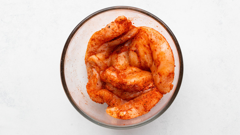 Spice-covered chicken breasts in glass bowl