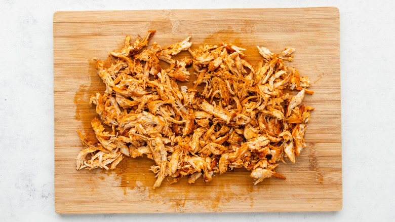 Shredded chicken on wooden cutting board