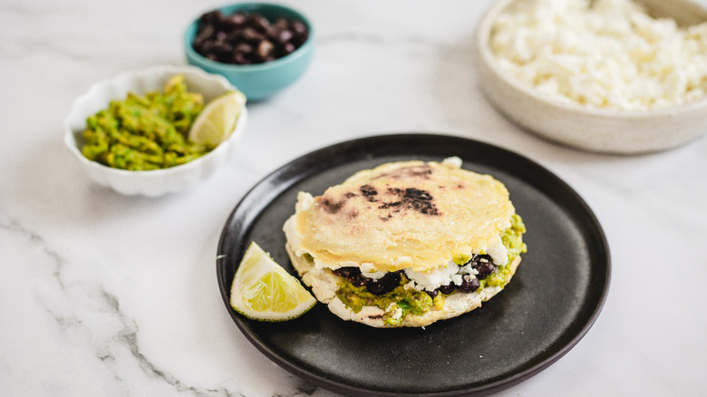 gordita on a plate with lime wedge and toppings