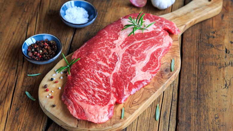 raw chuck eye steak on cutting board