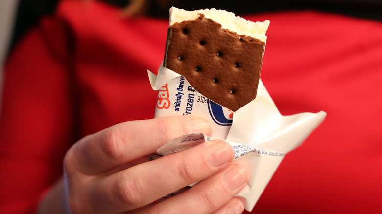 Hand holding half-eaten ice cream sandwich.