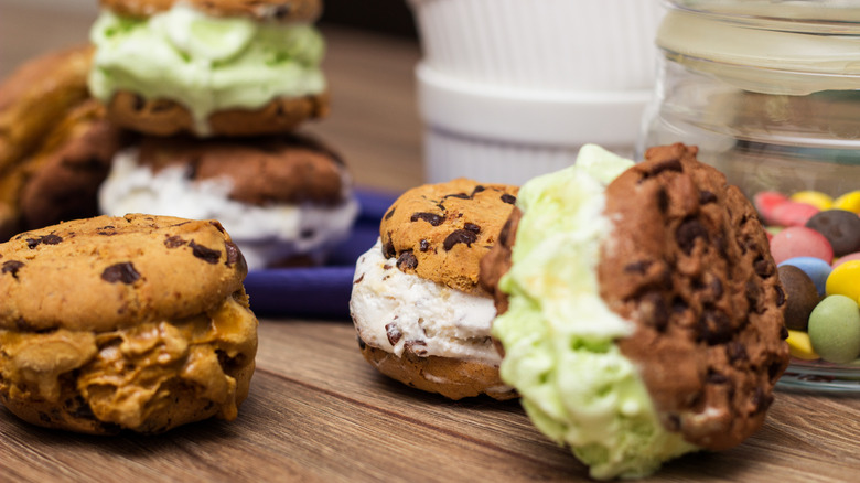 Round ice cream sandwiches of various flavors on table.
