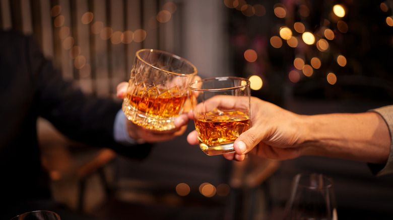 Clinking glasses of bourbon
