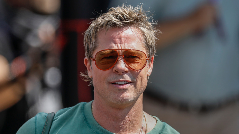 Brad Pitt wearing tinted glasses and a green t-shirt
