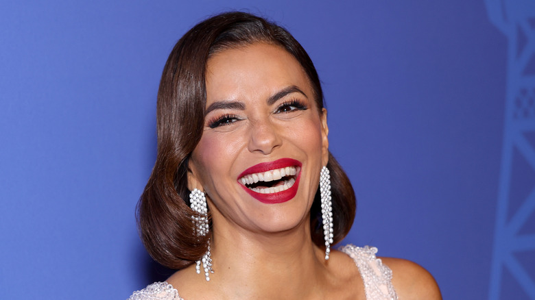 Eva Longoria wearing diamond jewelry and red lipstick and smiling