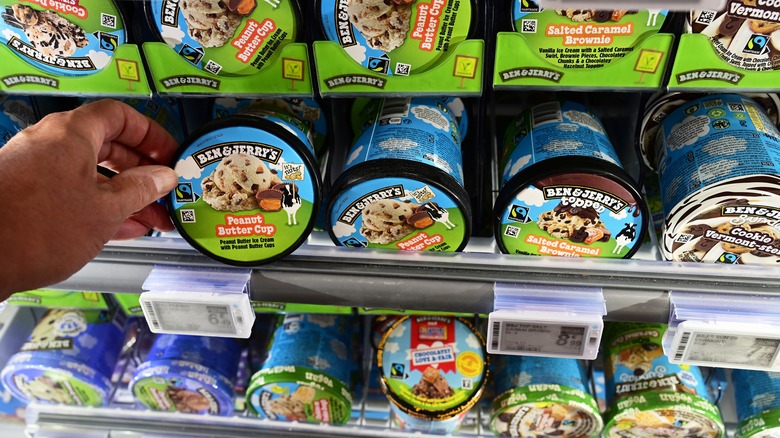 person selecting pint of Ben & Jerry's ice cream from freezer case
