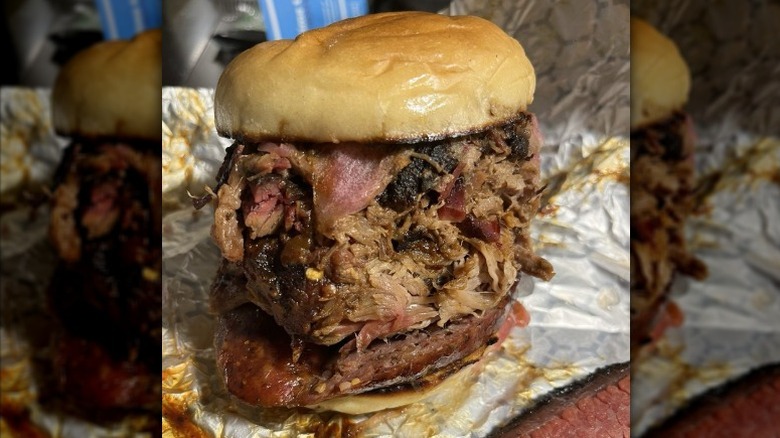 A sandwich with pulled pork, brisket, and sausage