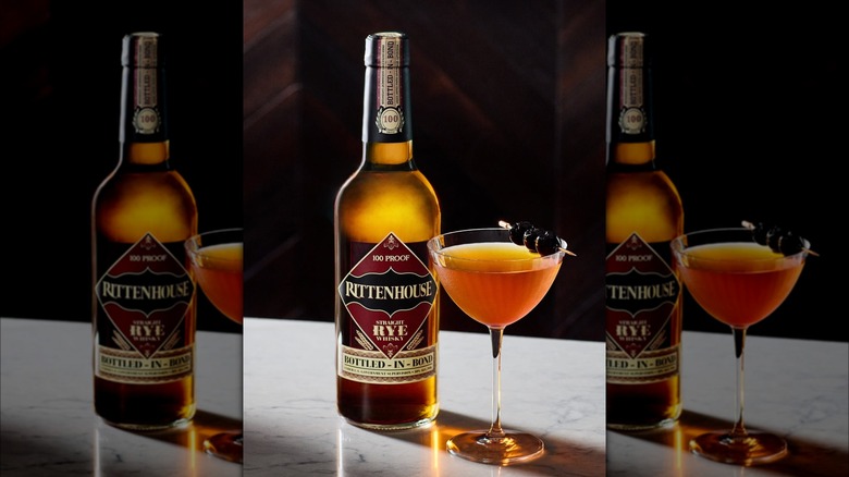 A bottle of Rittenhouse rye whiskey next to an old fashioned cocktail.