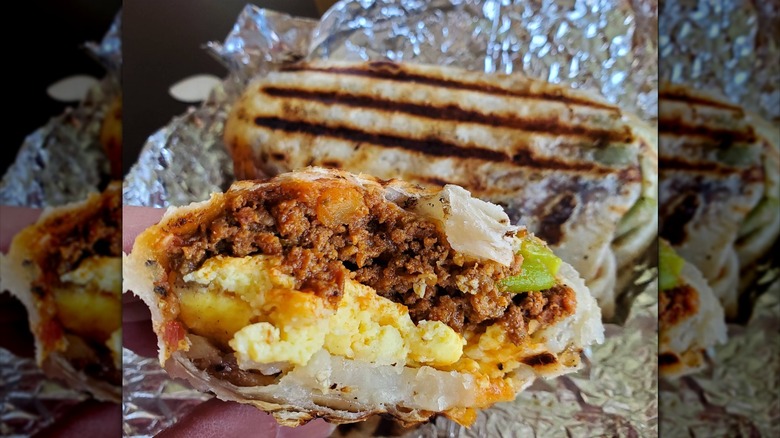 A close-up of a bitten-into breakfast burrito that has eggs, potatoes, and machaca inside