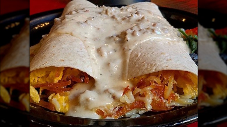 Two open-ended breakfast burritos smothered with a sausage gravy