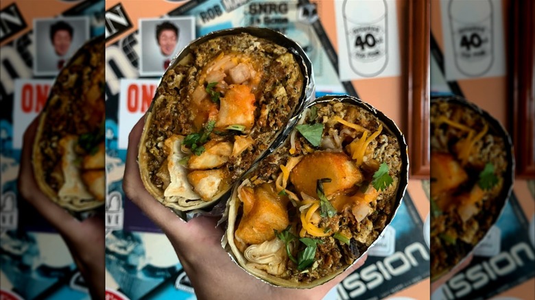 A breakfast burrito cut in half, filled with scrambled eggs, chorizo sausage, and picante sauce