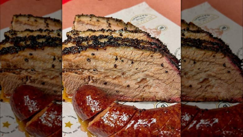 A close-up of Ray's famous sliced brisket alongside one of its beloved cheddar jalapeño sausages
