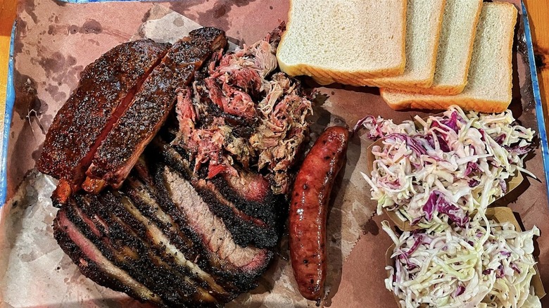 Tray of pork ribs, sausage, and beef brisket with coleslaw and white bread from Franklin Barbecue