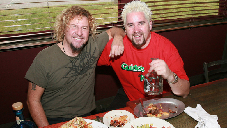 Guy Fieri smiles for camera while sharing a meal with Sammy Hagar at restaurant