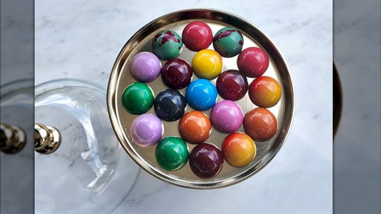 Round tray of glossy, colorful chocolates.
