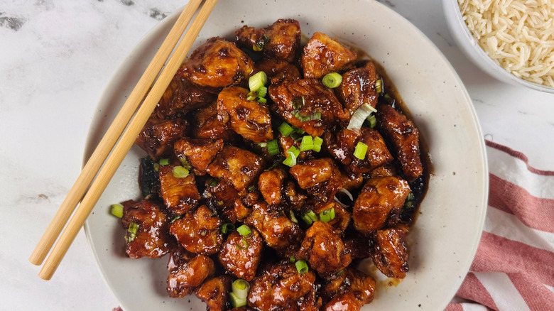 Saucy chicken pieces in bowl with chopsticks