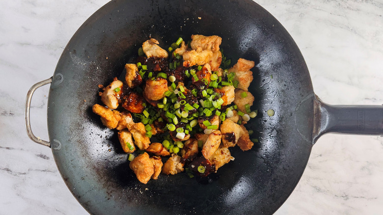 Chicken pieces with sauce and scallions in wok