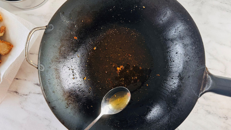 Spoon removing oil from wok
