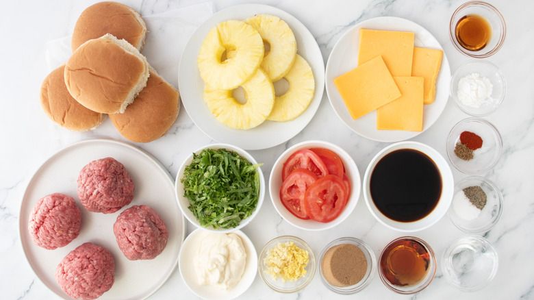Burger buns, pineapple rings, cheese slices, and other Red Robin Banzai burger ingredients laid out