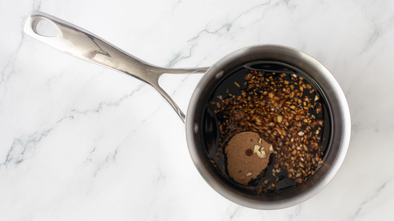 Aerial view of teriyaki sauce ingredients in saucepan on top of marble surface