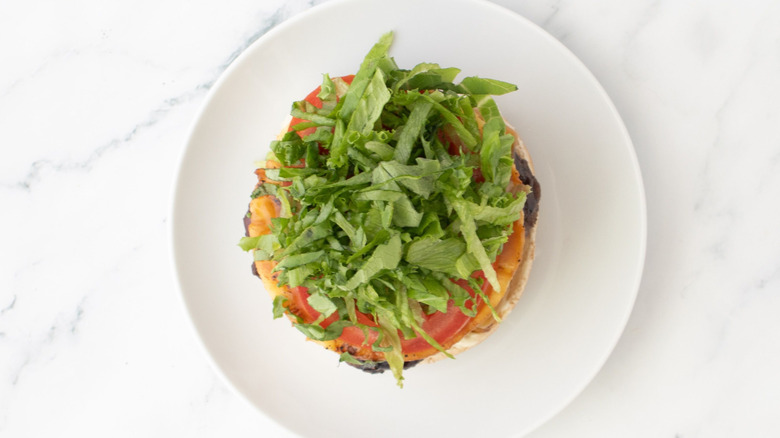 Open burger with lettuce and tomato on plate