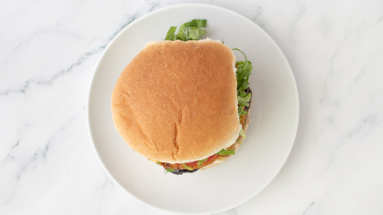Burger with lettuce and tomato sitting on plate