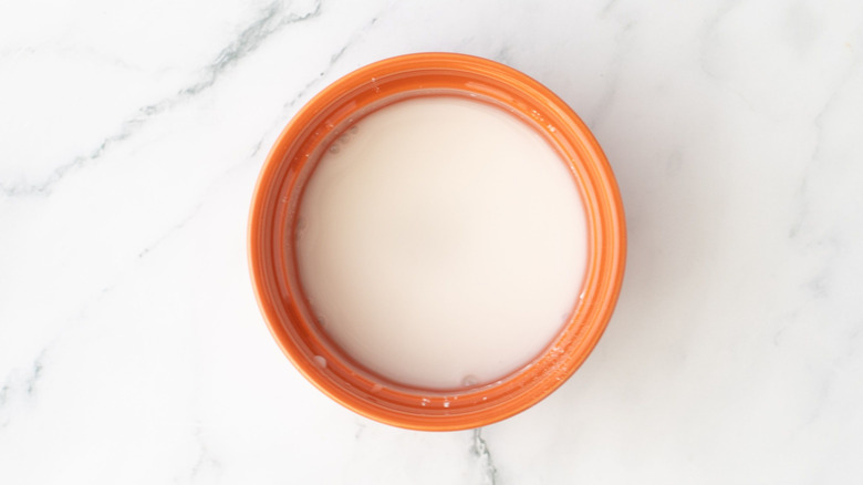 Cornstarch slurry in an orange bowl on top of a marble surface
