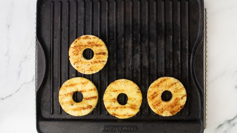Aerial view of four grilled pineapple rings on grill pan