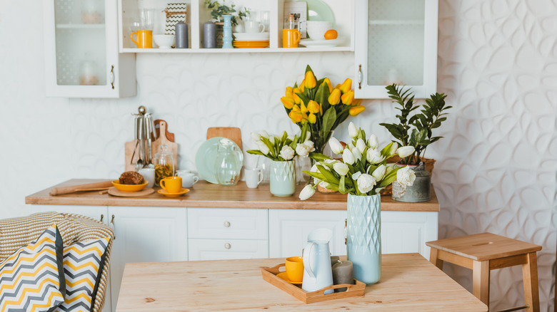 A kitchen decorated with colorful items and assorted spring flowers in vases.