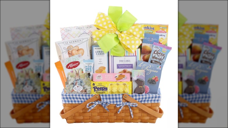 Wicker basket with assorted Easter treats and candy against white background.