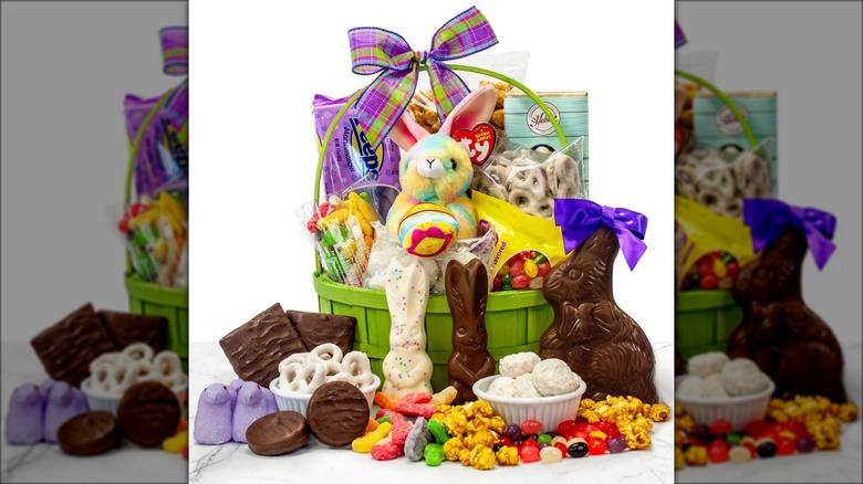 Easter basket with assorted treats, candy, and a plush bunny against white background.