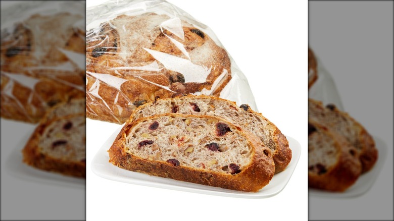 Plate of sliced cranberry walnut bread against white background.