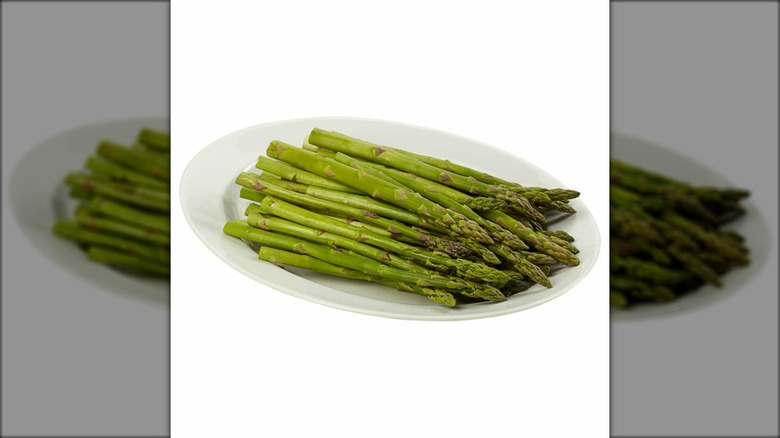 Plate of asparagus stalks against white background.
