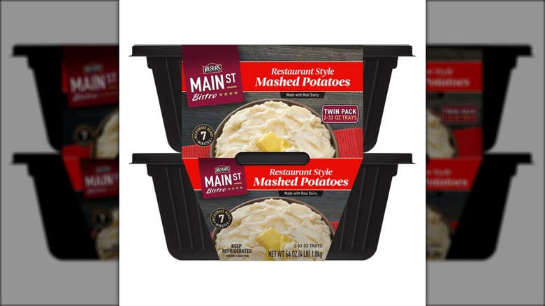 Two packages of premade mashed potatoes against white background.