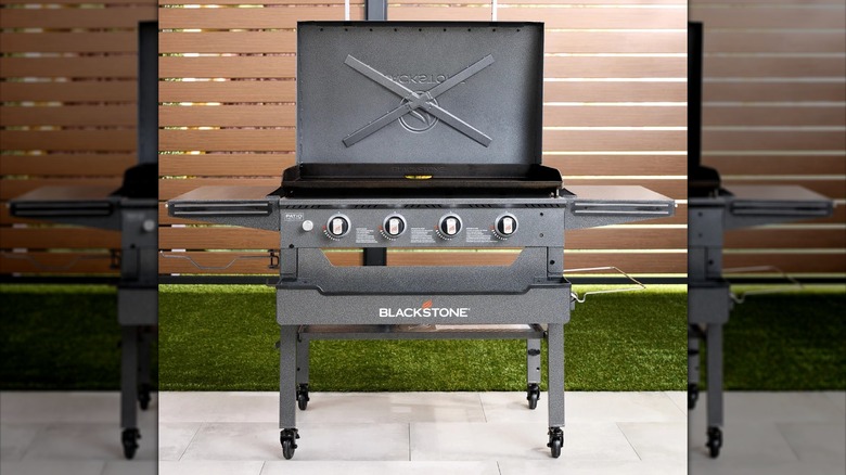 Large outdoor gas grill on patio with wood fence in the background