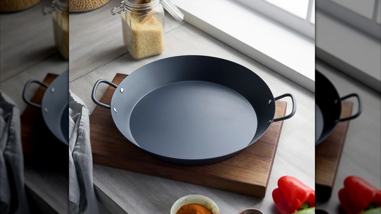 Paella pan on cutting board surrounded by peppers and spices