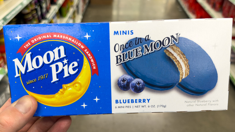 A person holding MoonPie Once in a Blue Moon mini pies in a Dollar Store aisle