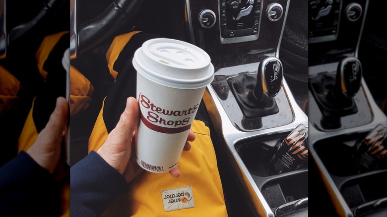 person holding a Stewart's Shops coffee mug in a car