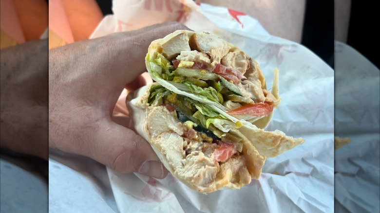 Man holding a Wawa hoagie with chicken and vegetables