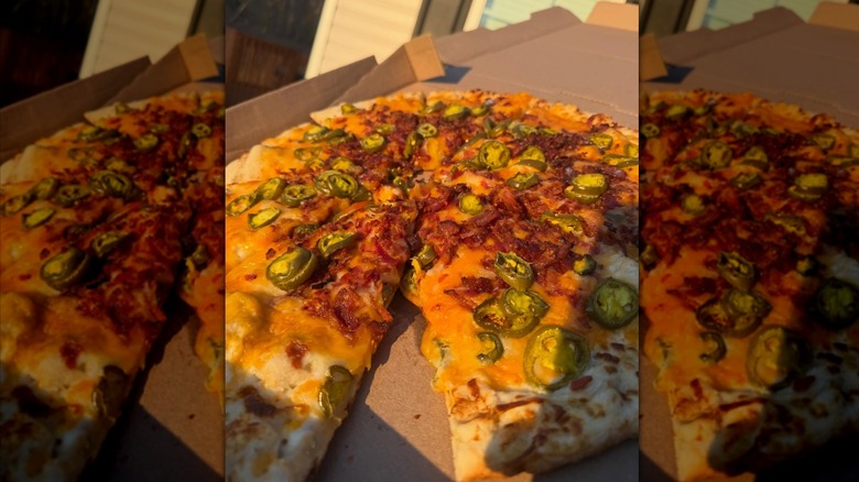 open box of pizza with a jalapeño, bacon, and cheese pizza inside