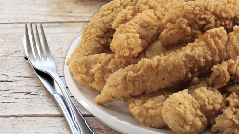 Plate of fried chicken with fork and knife