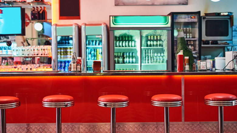 Inside of a retro diner with red stools and counter