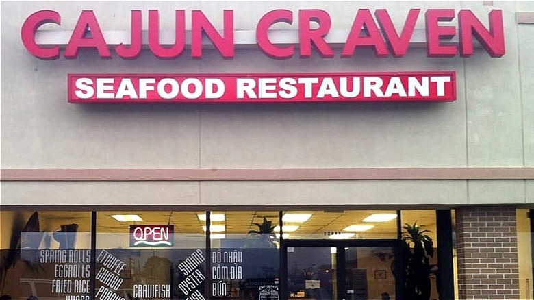 A strip mall restaurant with red block letters advertising the name Cajun Craven
